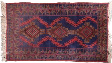 A dark blue ground Balouch style rug with diamond medallions on geometric patterned ground and red