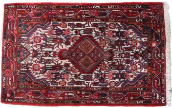 A cream ground Balouch style rug with red central medallion on geometric patterned ground and