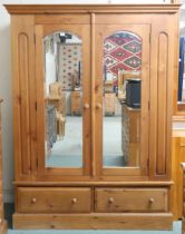 A contemporary pine two door wardrobe with moulded cornice over pair of mirrored doors over pair