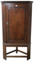 A Victorian oak corner cabinet with moulded cornice over single door concealing three shaped