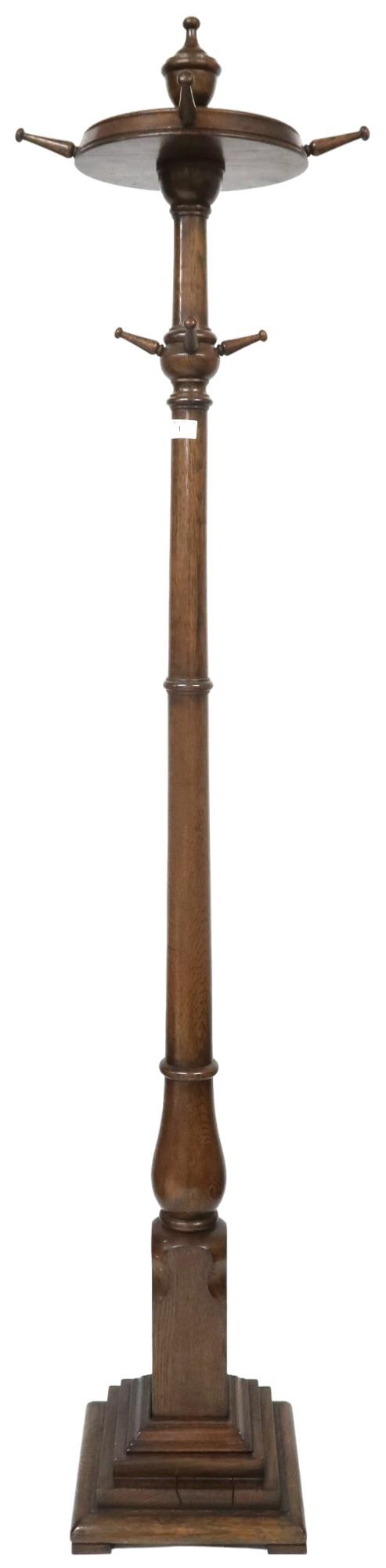 An early 20th century stained oak coat stand with turned finial top over four revolving pegs (one