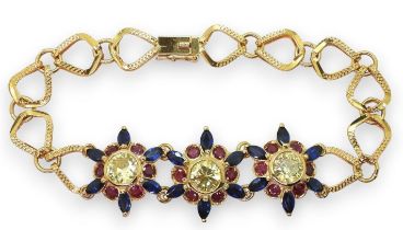 A 18CT GOLD FLOWER BRACELET the three central flowers are set with sapphires, rubies and pale yellow