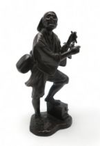 A JAPANESE BRONZE MODEL OF A MUSICIAN standing and with instrument slung over his shoulder and wit