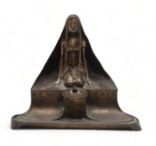 A CONTINENTAL ART NOUVEAU BRONZE INKWELL AND PEN TRAY modelled as a kneeling maiden wearing a cloak,