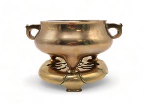 A CHINESE BRASS CENSER AND STAND The bulbous body cast with scroll handles and on tripod legs,