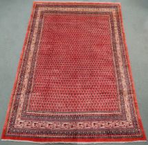 A RED GROUND ARDABIL RUG with multicoloured geometric borders, 312cm long x 215cm wide Condition