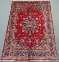 A RED GROUND TABRIZ RUG with dark blue and beige flower head central medallion, matching spandrels