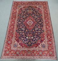 A DARK BLUE GROUND KASHAN RUG With red and cream diamond central medallion and matching spandrels on