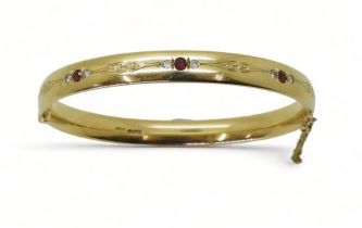 RUBY AND DIAMOND BANGLE mounted in heavy gauge solid 9ct gold, grain set with six diamonds with an