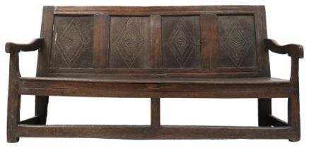 AN 18TH CENTURY OAK PROVINCIAL PANELLED BACK SETTLE  with four carved panelled splat flanked by down