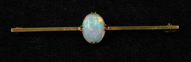 A 15CT GOLD OPAL BAR BROOCH set with an oval cabochon opal of 10mm x 8mm, length 5.5cm, weight 3.