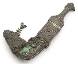 AN OMANI KHANJAR DAGGER The grip and scabbard clad with ornate white metal filigree, the slightly