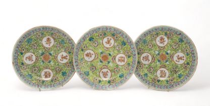 THREE CHINESE YELLOW GROUND PLATES Painted with flowers and scrolling foliage,divided by gilt shou