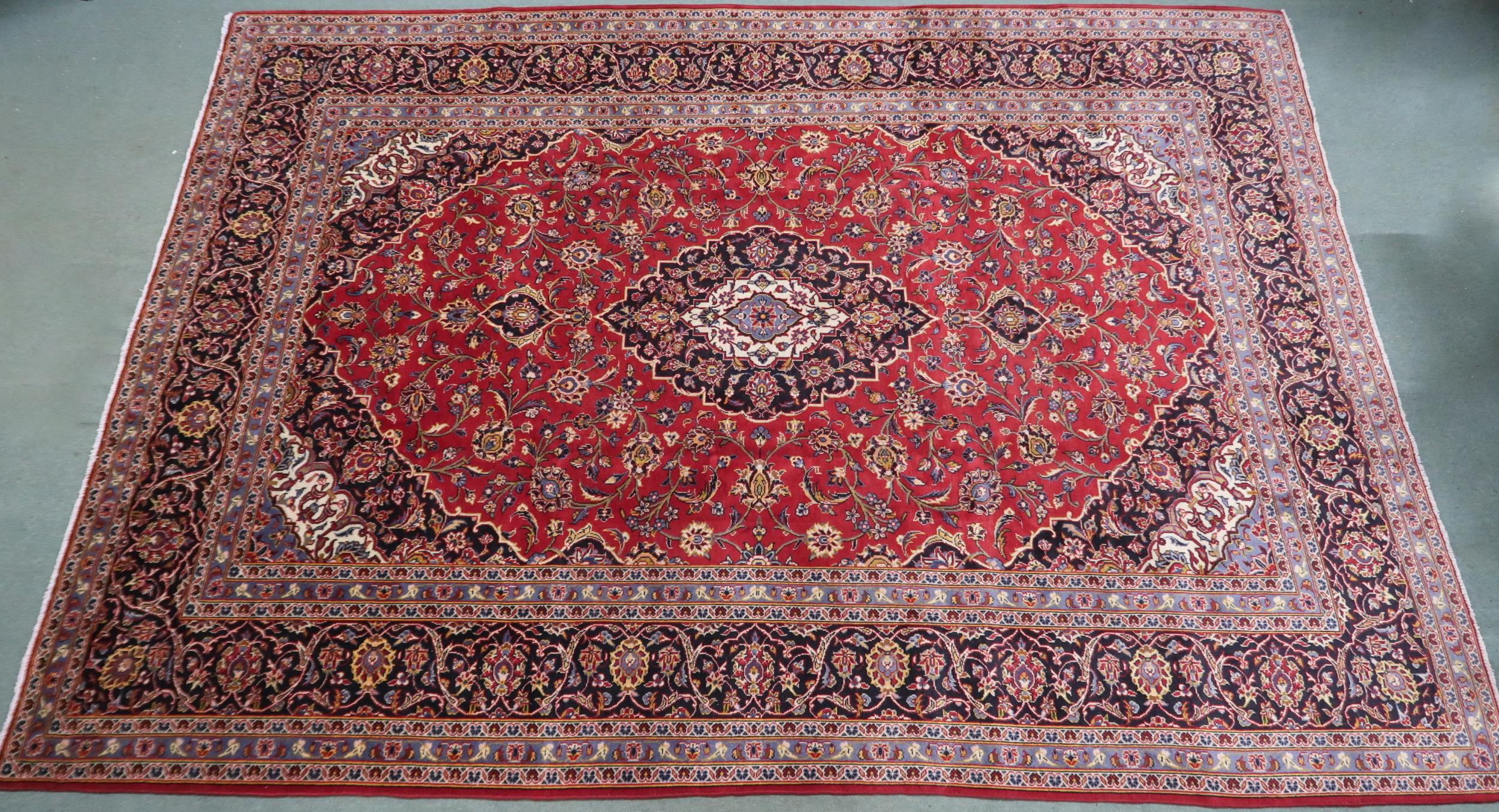 A RED GROUND KASHAN RUG  With dark blue and cream diamond central medallion and matching spandrels