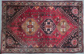 A red ground Qash'qai rug with three geometric medallions on foliate patterned ground within dark