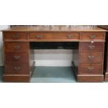 An early 20th century stained oak pedestal writing desk with brown skiver top over central long