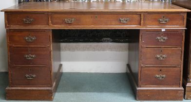 An early 20th century stained oak pedestal writing desk with brown skiver top over central long