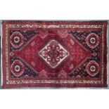 A red ground Qash'qai rug with cream diamond central medallion within dark blue spandrels and
