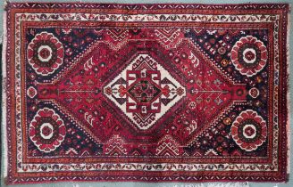 A red ground Qash'qai rug with cream diamond central medallion within dark blue spandrels and