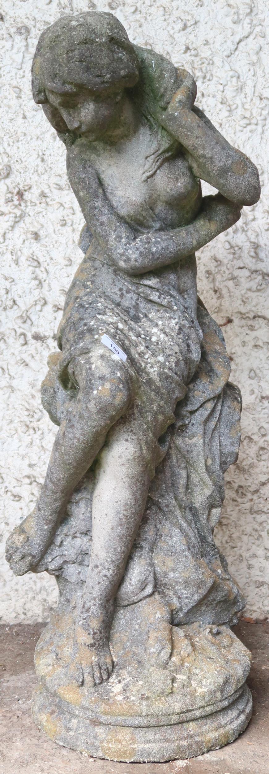 A 20th century reconstituted stone garden statue depicting a nude bather reclining on rocks, 85cm