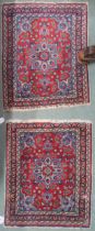 A pair of small red ground isfahan style rugs with light blue floral medallions, matching