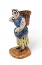 A early 19th century Scottish East Coast pottery fishwife figure, modelled carrying a basket of fish