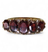 A 9ct gold garnet five stone classic scroll ring with diamond accents, size M1/2 weight 4.3gms