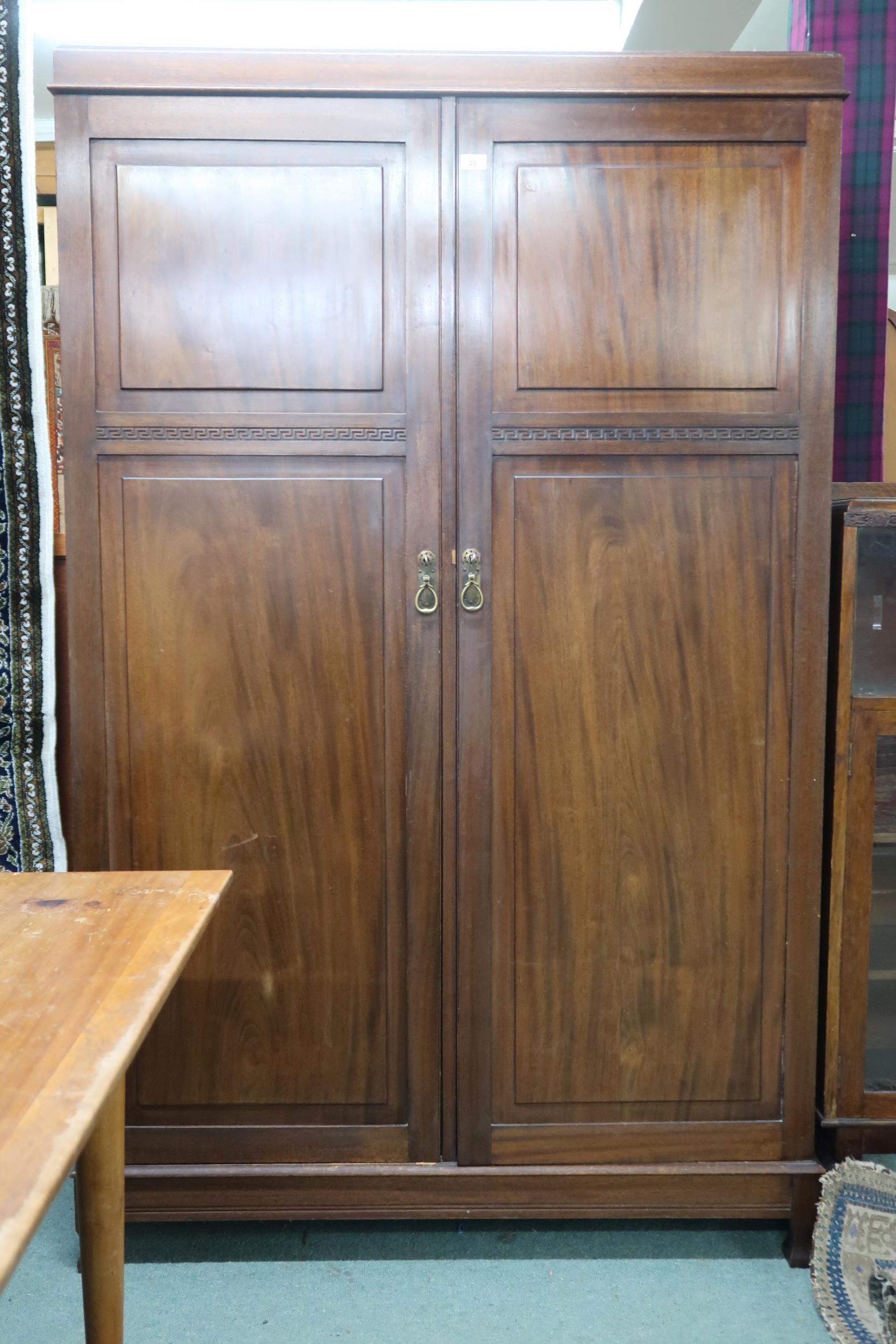 An early 20th century mahogany compactum wardrobe with pair of doors carved with Grecian key