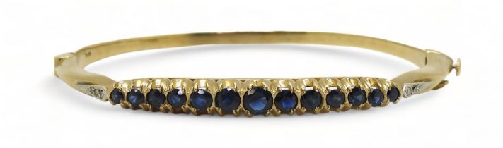 A Sapphire and diamond bangle with 9ct gold hallmarks for London 1987. Inner diameter 5.7cm x 5.2cm,