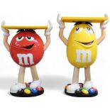 A lot comprising mixed pair of Mars M&M red and yellow advertising standees holding fixed serving