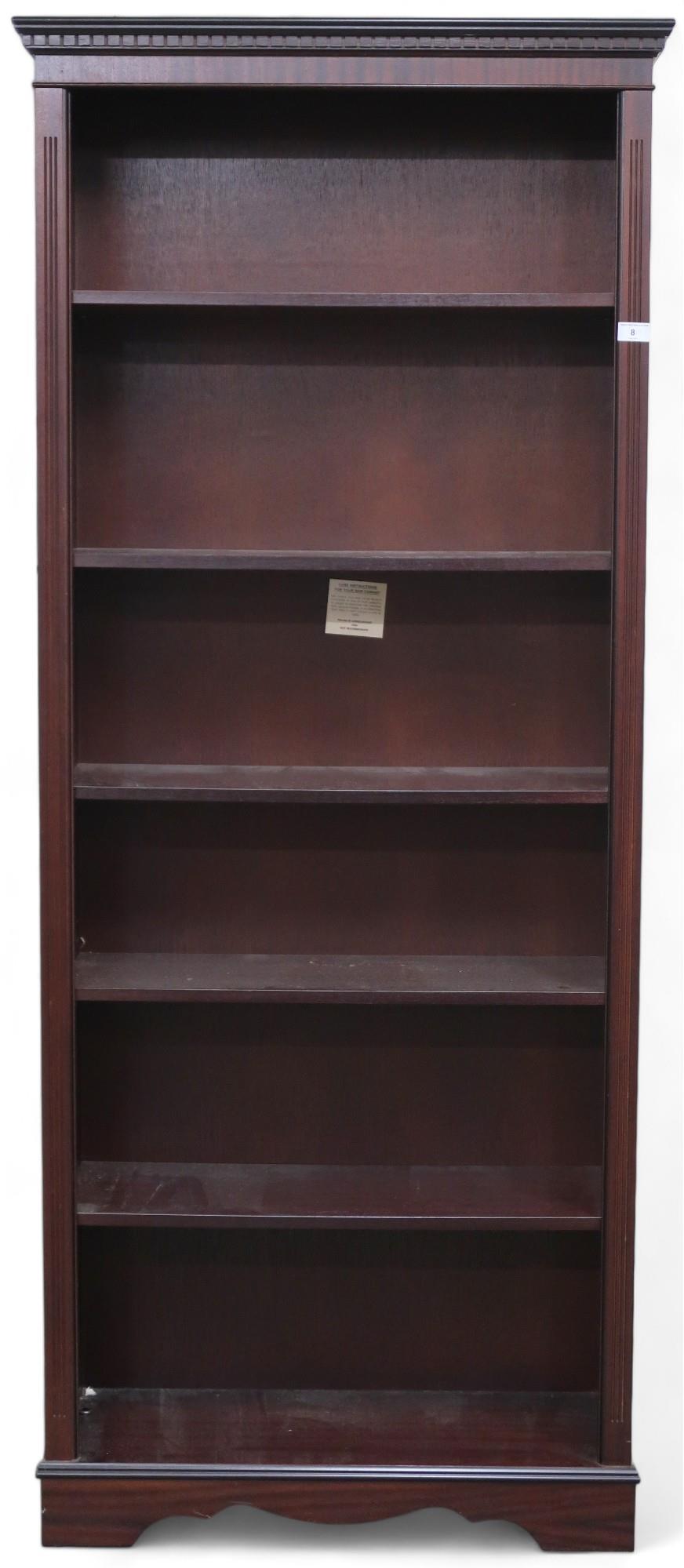 A 20th century mahogany veneered open bookcase with dentil cornice over five adjustable shelves on