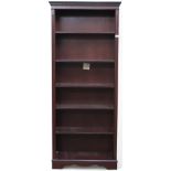 A 20th century mahogany veneered open bookcase with dentil cornice over five adjustable shelves on