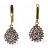 A pair of 10k gold diamond drop earrings with continental hoop closure, set with estimated approx