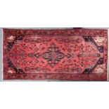 A red ground Hamadan runner with dark central medallion, matching spandrels on floral pattern