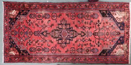 A red ground Hamadan runner with dark central medallion, matching spandrels on floral pattern