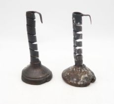 A pair of 17th/18th century iron "pig tail" candlesticks, set upon fruitwood bases, each measuring