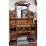 A late Victorian mahogany mirrored back display cabinet with architectural surmount over central