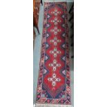 A red ground Shiraz runner with seven cruciform medallions, dark blue spandrels within multicoloured