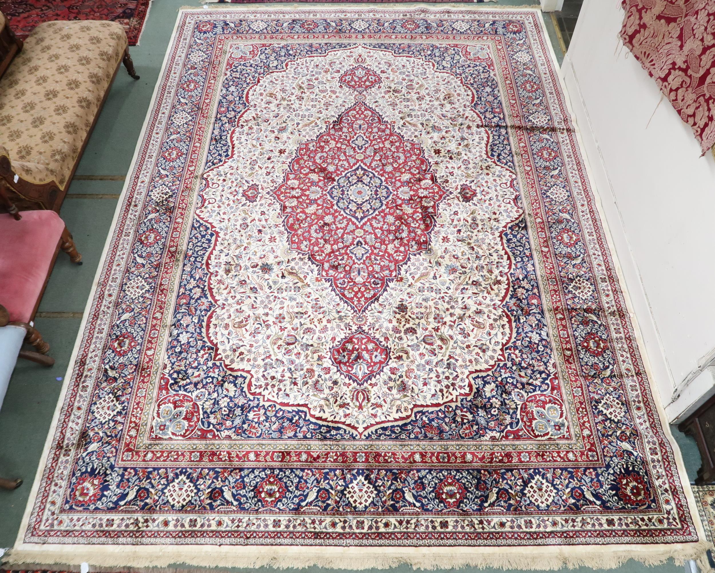 An Ivory ground full pile Cashmere rug with red central medallion, dark blue spandrels on floral