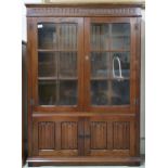 A 20th century stained oak glazed bookcase with pair of glazed doors over pair of linenfold