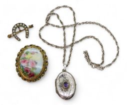 A yellow metal horseshoe brooch, weight 3.7gms, a silver amethyst set locket and chain, and a