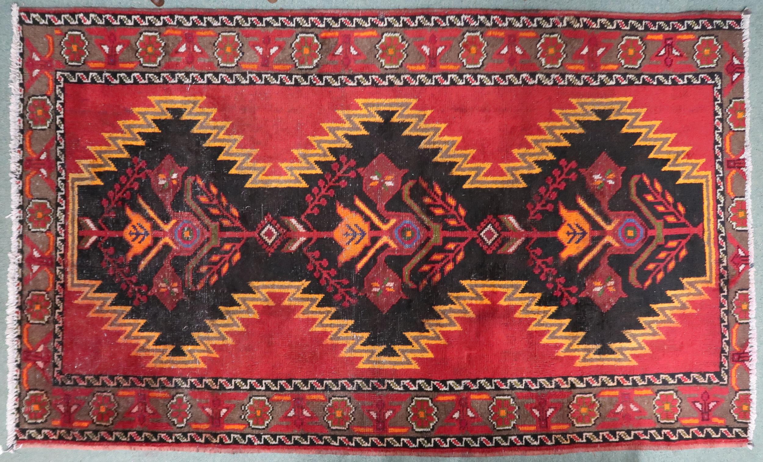 A red and black geometric ground Persian Village rug with geometric floral/foliate design with