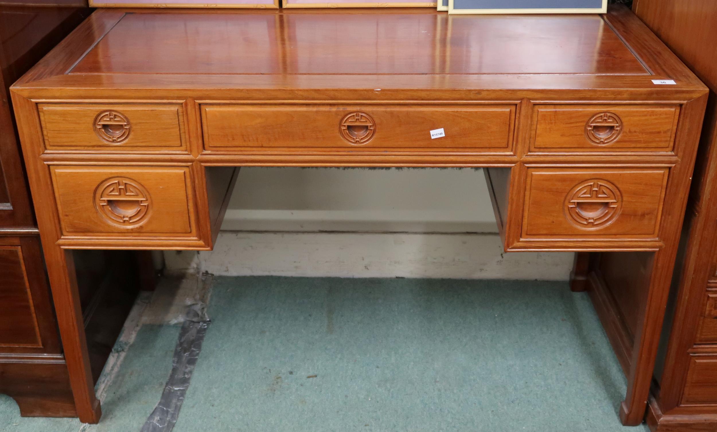 A contemporary Oriental hardwood writing desk with long central drawer flanked by two short