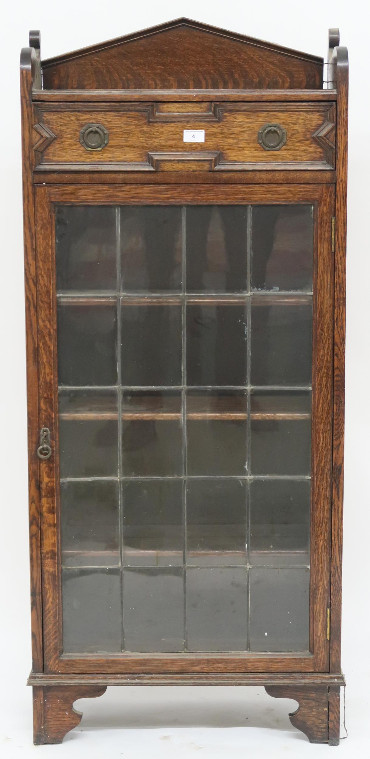 An early 20th century oak Jacobean style bookcase with single drawer over leaded glass door on