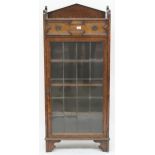 An early 20th century oak Jacobean style bookcase with single drawer over leaded glass door on