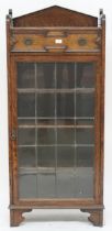 An early 20th century oak Jacobean style bookcase with single drawer over leaded glass door on