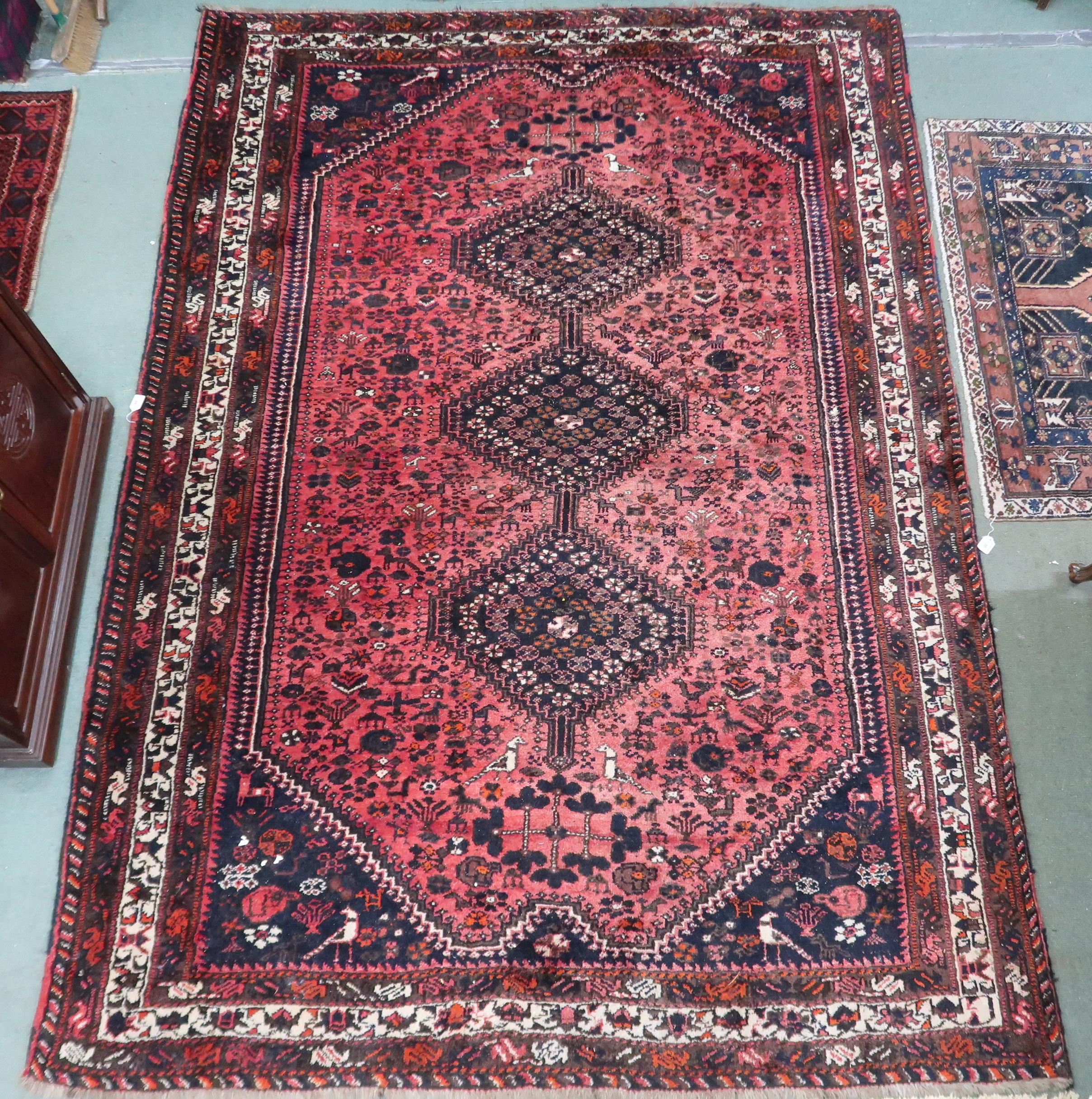 A red ground Hamadan rug with three diamond form medallions and dark blue spandrels within
