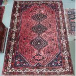 A red ground Hamadan rug with three diamond form medallions and dark blue spandrels within