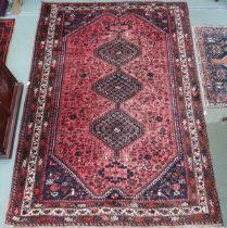 A red ground Hamadan rug with three diamond form medallions and dark blue spandrels within