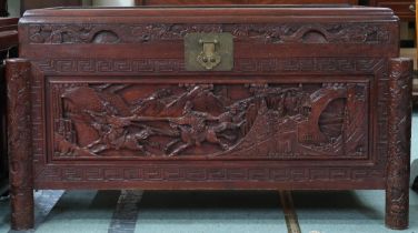 A 20th century Chinese camphorwood blanket chest carved with stylized battle scenes to top and front